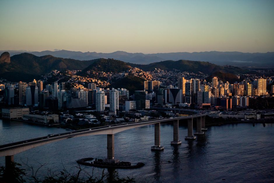 Pessoa analisando gráficos de desempenho em um tablet, com a cidade de Porto Alegre ao fundo